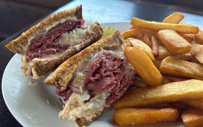 reuben sandwich on a plate with steak cut fries