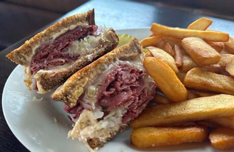reuben sandwich on a plate with steak cut fries