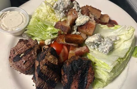 cuts of steak on a plate with wedges of lettuce